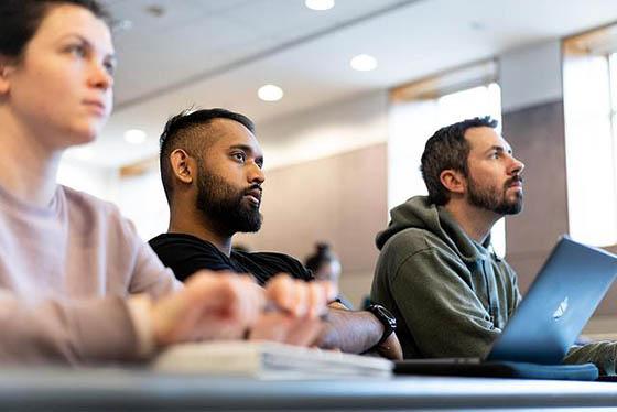 Photo of a three Chatham University students in a classroom, paying attention to an off-screen instructor